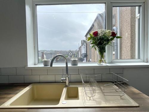 a kitchen sink with a vase of flowers in a window at HNFC Stays - Shoreline Flat in South Shields