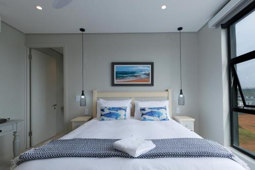 a bedroom with a large white bed with blue pillows at Husk 17 - Sheffield Beach in Ballito