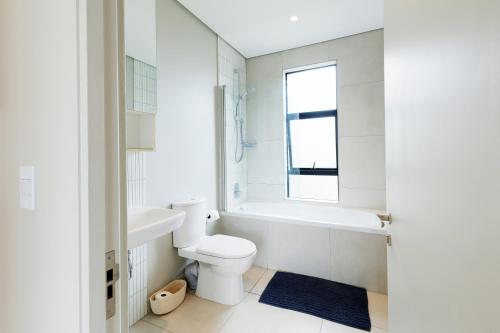 a bathroom with a toilet and a tub and a sink at Husk 17 - Sheffield Beach in Ballito