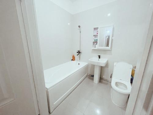 a bathroom with a tub and a toilet and a sink at Sunrise Guesthouse UB in Ulaanbaatar