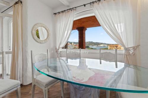 a glass table in a room with a window at Yacht Terrace - Exclusive Waterfront View Porto Cervo Center - by Coral Property in Porto Cervo