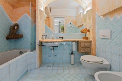 a blue bathroom with a toilet and a sink at Yacht Terrace - Exclusive Waterfront View Porto Cervo Center - by Coral Property in Porto Cervo