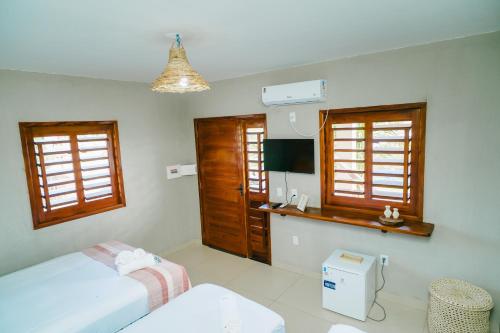 a bedroom with two beds and a desk and windows at Chalé sol de Macapá 1- Refúgio Pertinho do Mar in Luis Correia