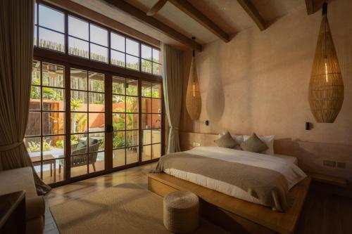 ein Schlafzimmer mit einem Bett und einem großen Fenster in der Unterkunft Lio Lio Suites Private Pools in El Nido