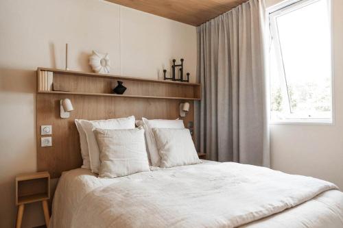 a bedroom with a bed with white sheets and a window at Mobile-Home Living in Gilsdorf