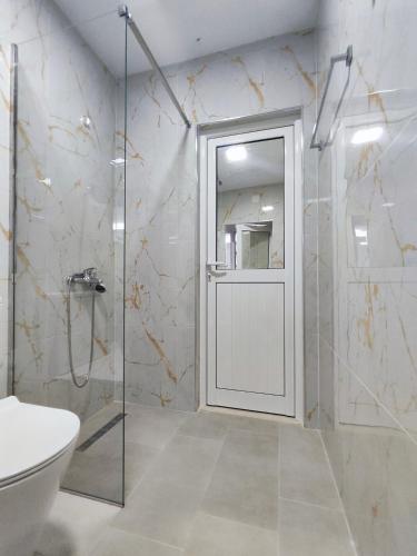 a bathroom with a shower and a toilet and a glass door at Sokaku Apartment in Gjirokastër