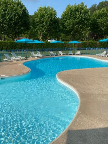 a swimming pool with chairs and blue umbrellas at Chambres les 4 saisons in Oust
