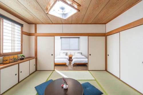 a living room with a table and a room with two beds at Guest Houseふくふく in Shimonoseki