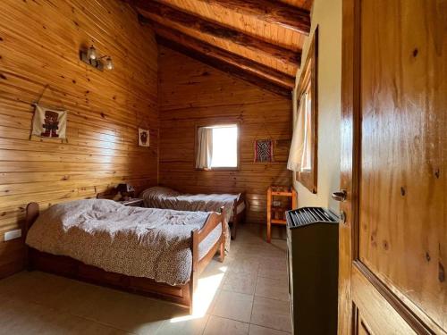 a bedroom with two beds in a wooden cabin at Cabañas Las Cascadas in Caviahue