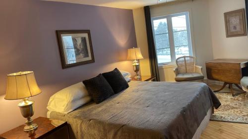 a bedroom with a bed with two lamps and a desk at Le Saint Louis de lotbinière in Lotbinière
