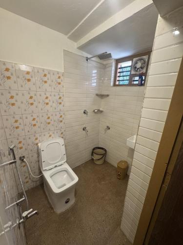 a white bathroom with a toilet and a shower at Hibisco Hideout in Meenangadi