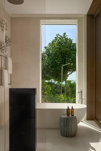 a bathroom with a tub and a large window at SLS The Red Sea in Ḩanak