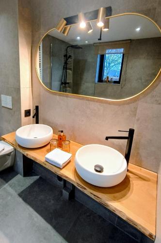 a bathroom with two sinks and a large mirror at Au Coin du Bois in Theux