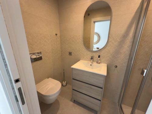 a bathroom with a toilet and a sink and a mirror at Seafront 2B Apartment with Pool, Spa & Gym Torrox in Torrox