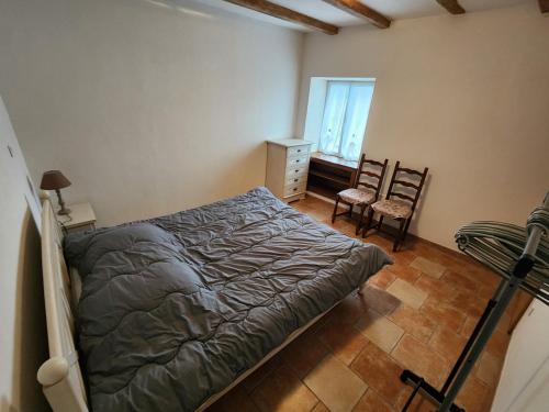 a bedroom with a bed and two chairs and a window at La maison bleue in Velet