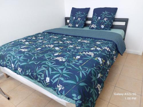 un letto con una coperta blu con fiori bianchi sopra di Duleing House a Orléans