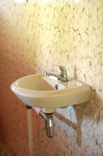 a white sink in a bathroom with white tiles at Swindo Homestay 77, Room 11 in Berastagi