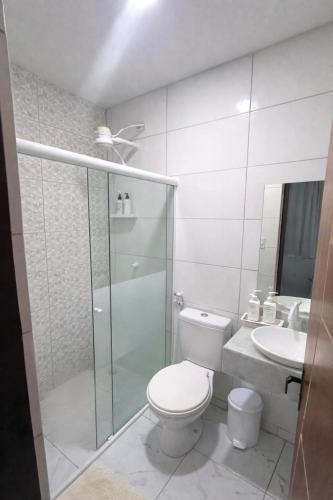 a white bathroom with a toilet and a sink at Pousada Doce Mar in Maragogi