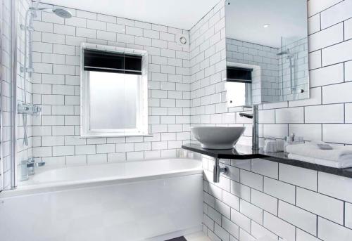 a white bathroom with a tub and a sink at Redesdale Arms Hotel in Moreton in Marsh