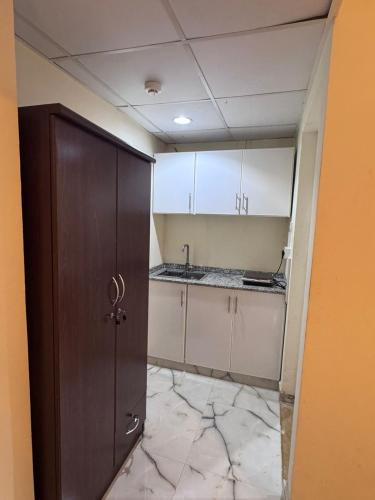 a kitchen with white cabinets and a brown door at Cozy Studio Apartment near union Metro in Dubai