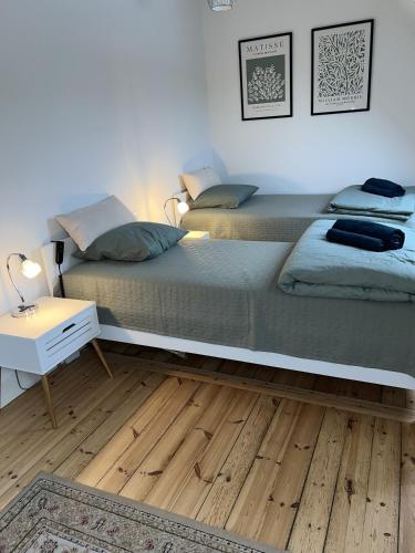 two beds in a bedroom with a wooden floor at Flot byhus tæt på Lalandia og Femern in Rødby