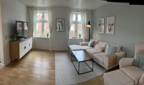 a living room with a couch and a table at Flot byhus tæt på Lalandia og Femern in Rødby