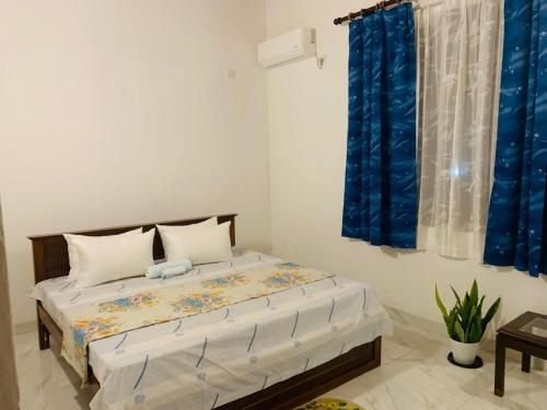 a bedroom with a large bed with blue curtains at Anjana Villa in Katunayaka
