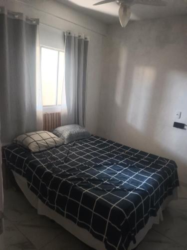 a bedroom with a bed with a blue plaid blanket at Casa familiar in Vespasiano