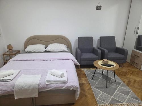 a bedroom with a bed and two chairs and a table at Apartman Studio 2 in Brčko