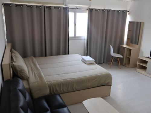a bedroom with a bed and a chair and a window at Hi Impact Muangthong T9 in Nonthaburi