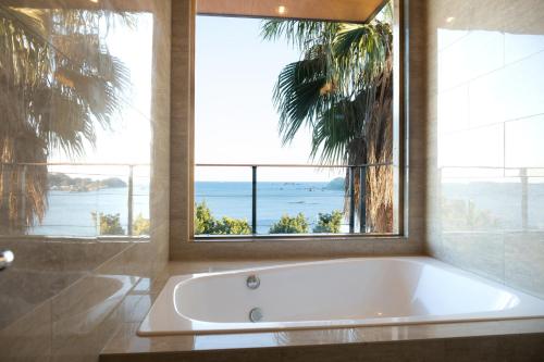 a bath tub in a bathroom with a large window at The House of Ocean in Nachikatsuura