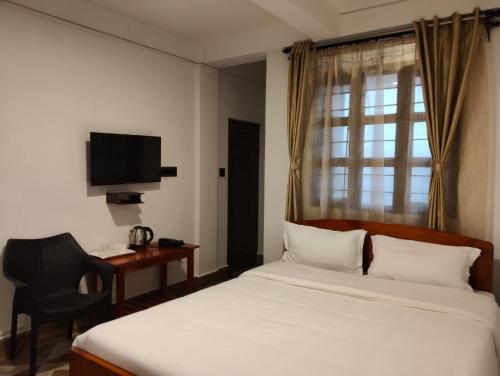 a bedroom with a bed and a desk and a television at Coralberry Inn in Jāmb