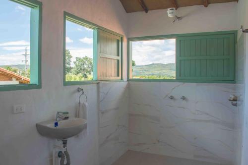 a bathroom with a sink and a shower and two windows at Trinitarios in Barichara