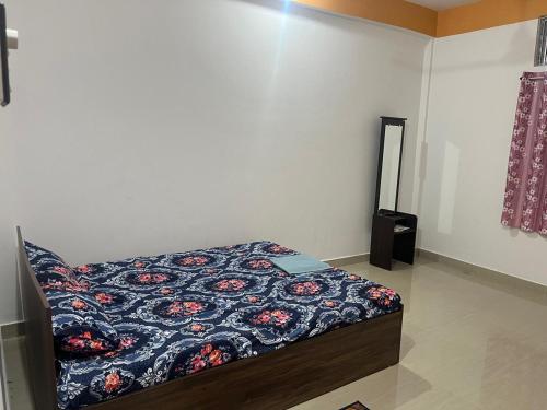 a bedroom with a bed with a flowered blanket at Jinkos Homestay with self cooking facility in Itānagar