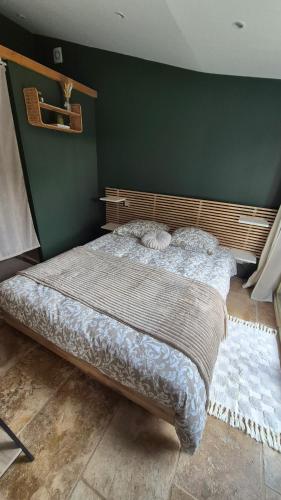 a bed in a bedroom with a green wall at Les cabanons de l'Oliveraie in Pernes-les-Fontaines