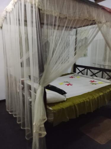 a bedroom with a canopy bed with white curtains at peacock Rest in Batapola