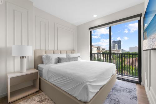 a white bedroom with a bed and a large window at The Avenue Coral Gables in Miami