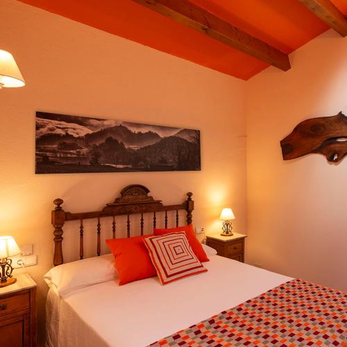 a bedroom with a bed with red pillows on it at Casatona in San Mateo de Bages