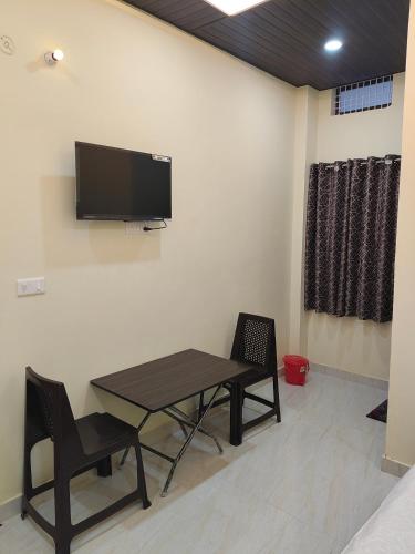 a room with a table and chairs and a tv on the wall at Sri Ram Shankar-Saryu Ghat in Ayodhya