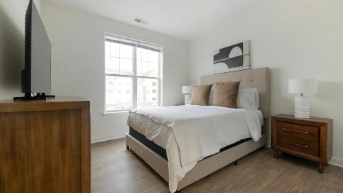 a white bedroom with a bed and a television at Landing Apartments - Prospect Hall in Frederick