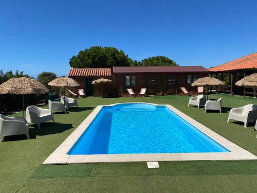 a swimming pool in a yard with chairs and umbrellas at Country Spot - Summer House in Porto Covo