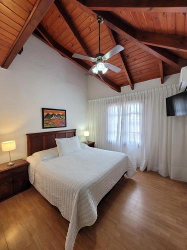 a bedroom with a white bed and a ceiling fan at Hotel L' Hirondelle in La Falda