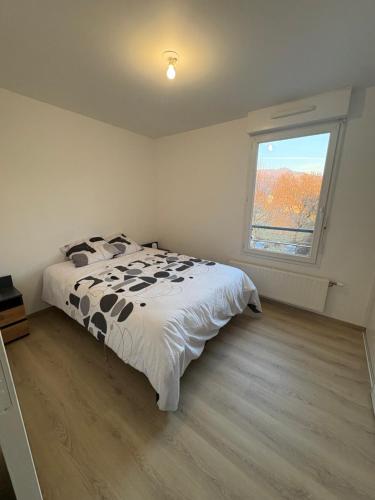 a bedroom with a bed with a black and white comforter at Appartement T2 Confort in Albertville