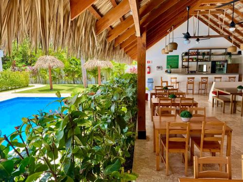 a restaurant with a pool and tables and chairs at La Curadiña - Encuentro Surf Hotel in Cabarete