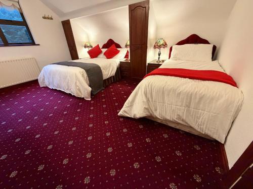 two beds in a hotel room with red carpet at Tullyeskar House - Monasterboice in Philipstown