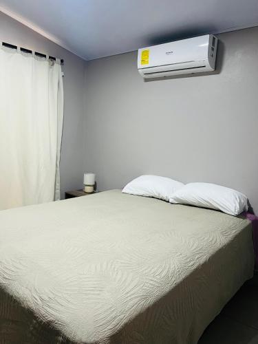 a bedroom with a bed with a air conditioner on the wall at Epic Arenal View House in Fortuna