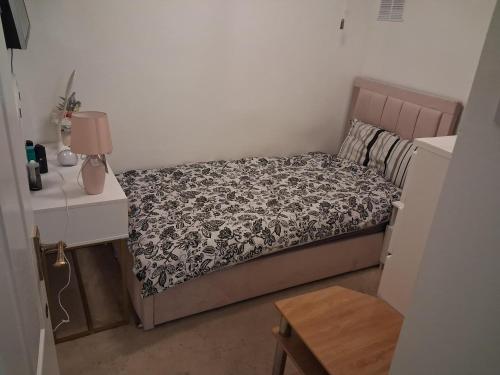 a small bedroom with a bed and a table at Cullen Sqaure in South Ockendon
