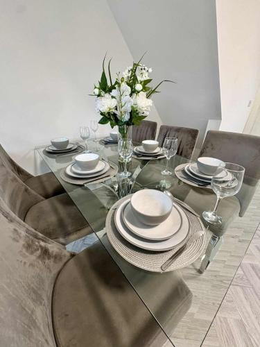 a dining room table with plates and a vase of flowers at The Sherwood Snug in Edwinstowe