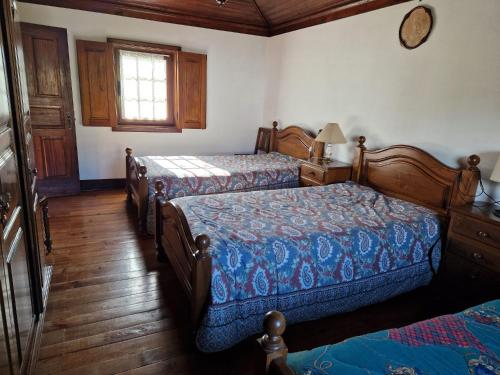 a bedroom with two beds and a window at Carneiro Country Houses Casa do Avô in Carneiro