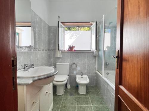 a bathroom with a sink and a toilet and a bath tub at Casa Nabia - Coastal Sanctuary in Ericeira